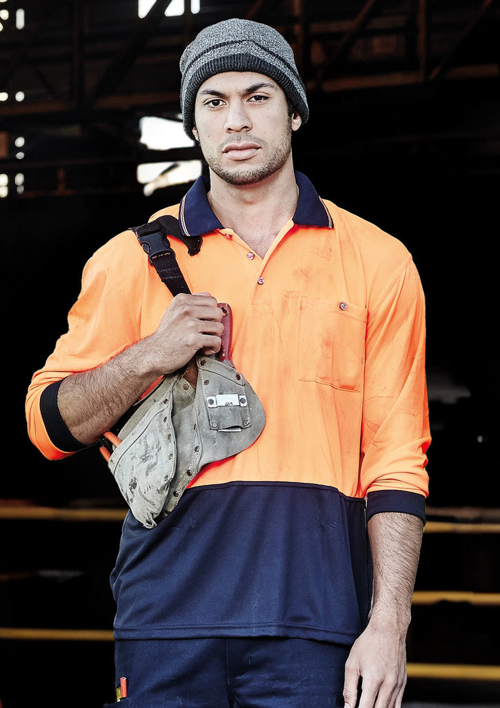 Syzmik worker wearing an orange and navy ZH232 hi-vis polo in an industrial setting